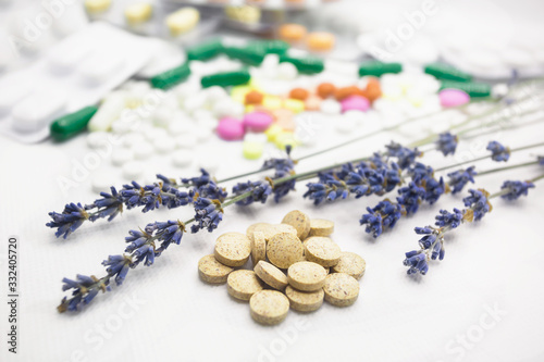 The concept of pills for treatment. Multi-colored pills on a white isolate. Hope for cure, hope for medicine. Daily dose. Herbal natural pills against chemistry. Lavender twigs.