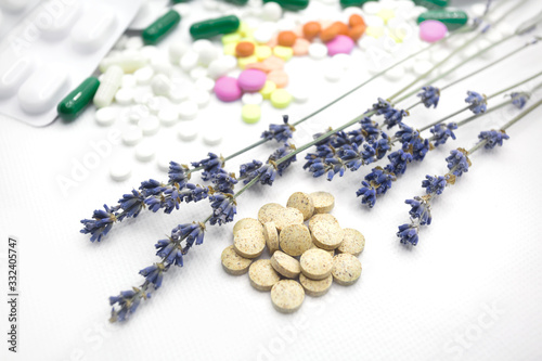 The concept of pills for treatment. Multi-colored pills on a white isolate. Hope for cure, hope for medicine. Daily dose. Herbal natural pills against chemistry. Lavender twigs.