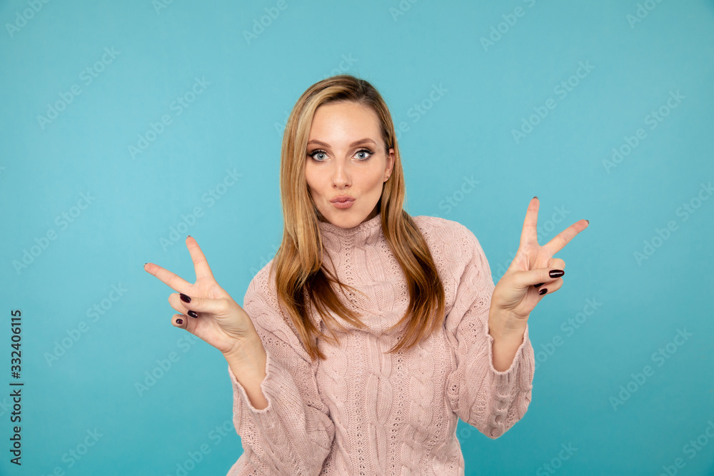 Stylish female model having fun and showing peace sign in the blue studio Stylish female model having fun and showing peace sign in the blue studio