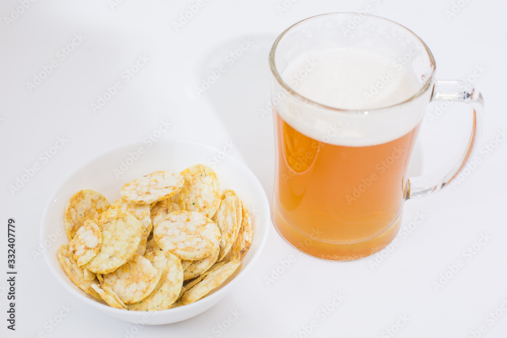 Beer mug full of beer and chips in a white plate on the white background Beer mug full of beer and chips in a white plate on the white background