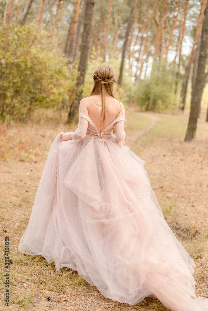 bride in pink dress walking in forest