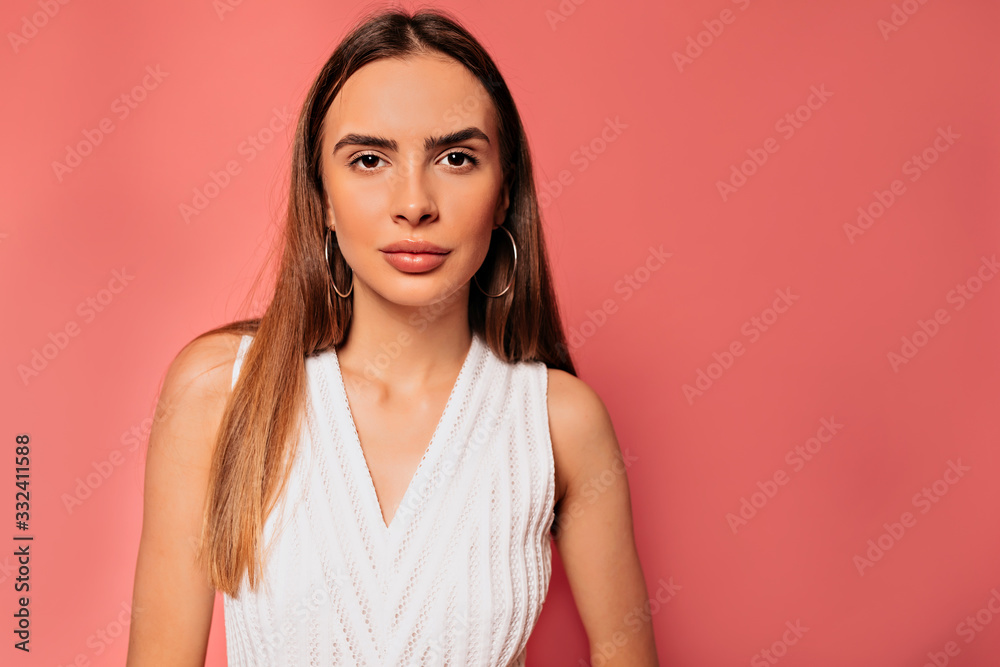 Close up portrait of attractive pretty woman with long hair wearing white t-shirt posing over pink background Close up portrait of attractive pretty woman with long hair wearing white t-shirt posing over pink background