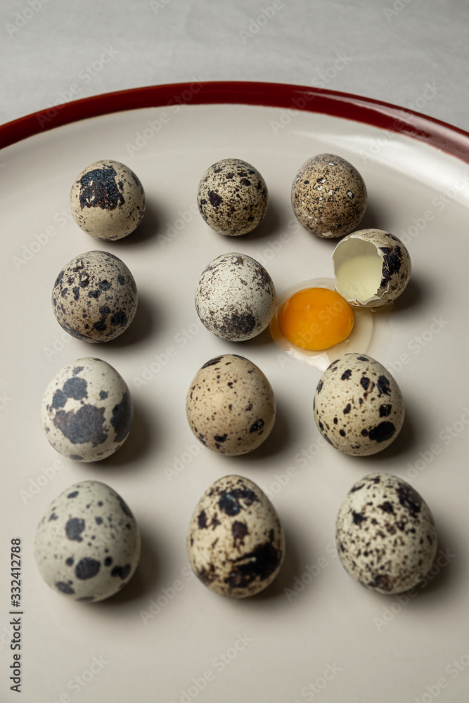 Obraz premium Quail eggs on white plate. One egg is broken.