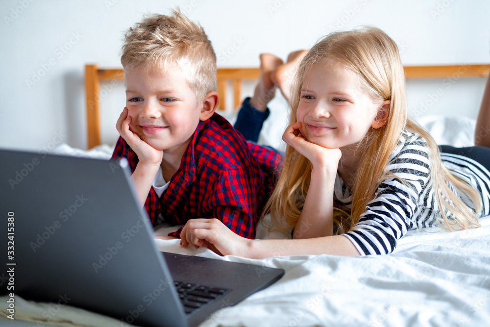 Distance learning online education. Schoolboy and girl studying at home with digital tablet laptop notebook and doing school homework. Sitting on bed with training books Distance learning online education. Schoolboy and girl studying at home with digital tablet laptop notebook and doing school homework. Sitting on bed with training books