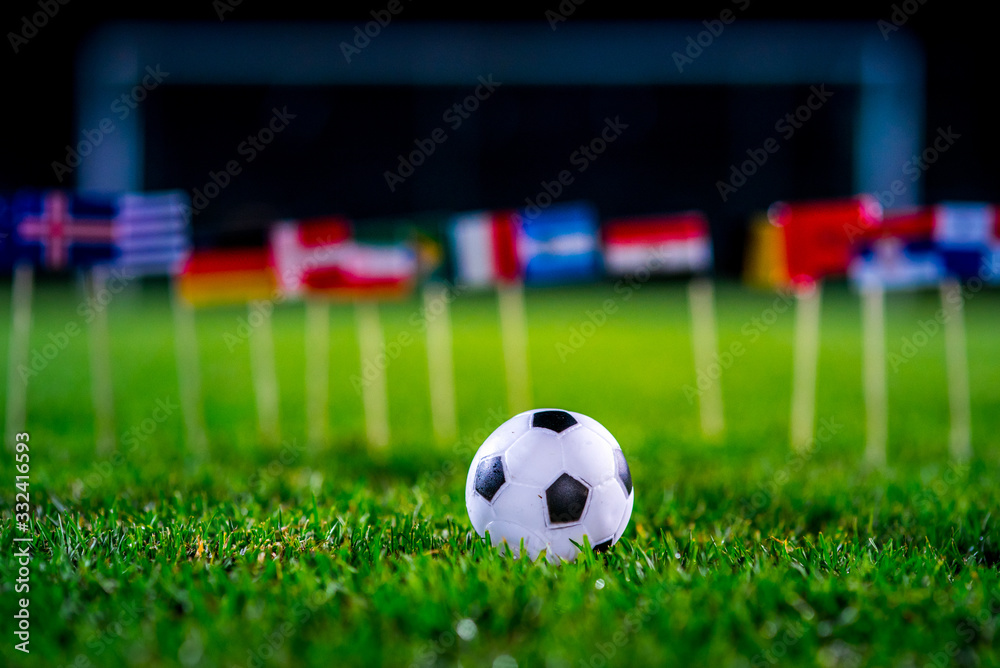 Football ball on green grass and all national flags of World Cup in Russia 2018.