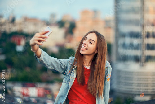 Teen girl on cityscape background making self portrait with her smart phone