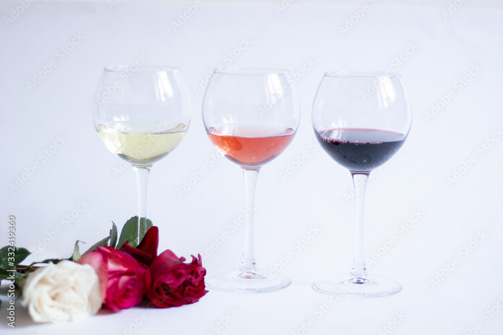 Three color wine glasses and rose flowers on white background Three color wine glasses and rose flowers on white background