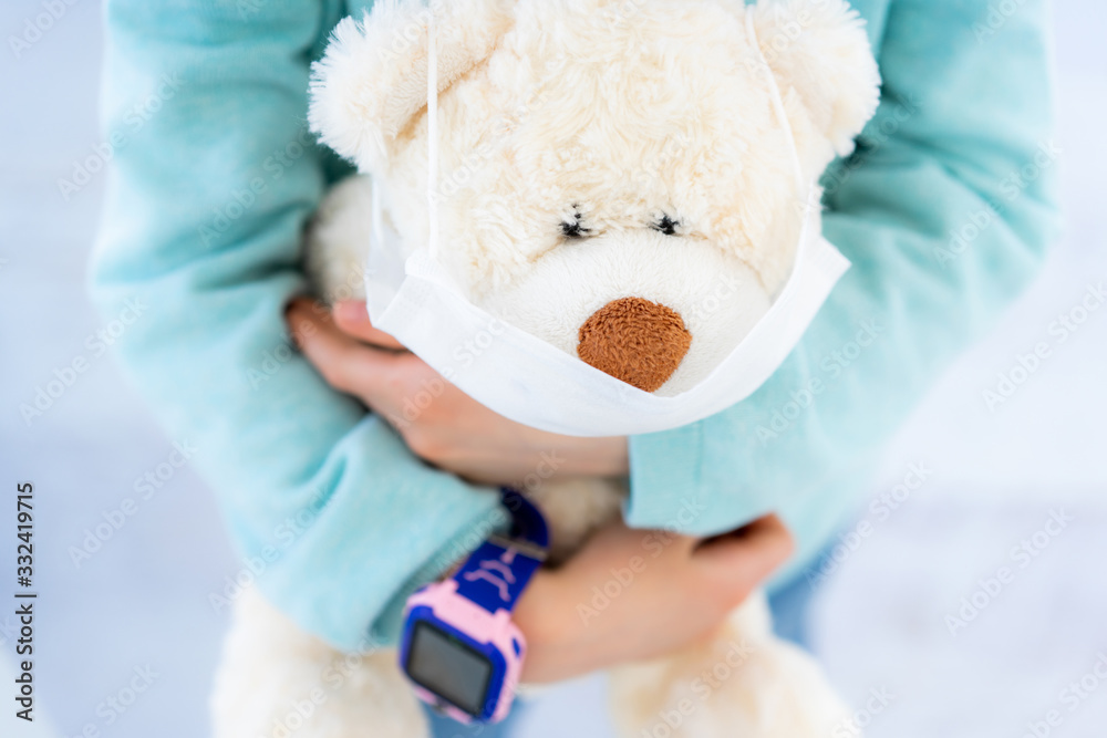 Teddy bear in medical mask in hands of girl