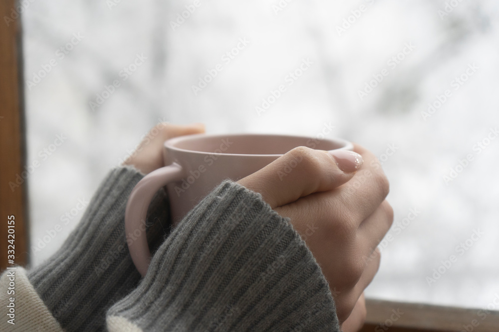 A cup of aromatic coffee in the hands of a girl, winter day