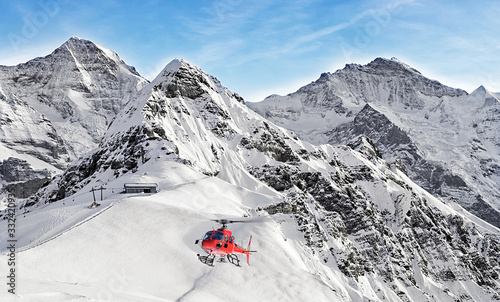 Red helicopter flying near swiss ski resort near Jungfrau mountain photo