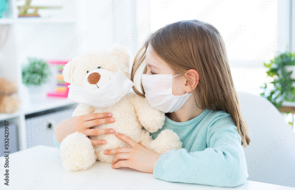 Cute little girl playing with teddy bear in light room