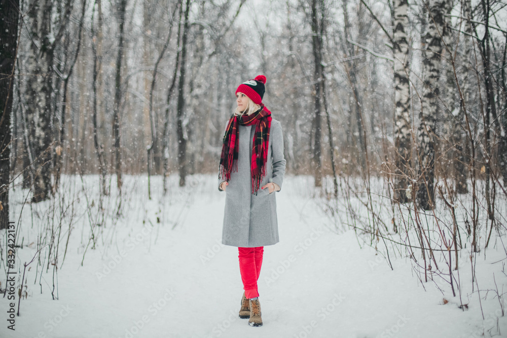 Girl in gray coat and red hat walking the winter park
