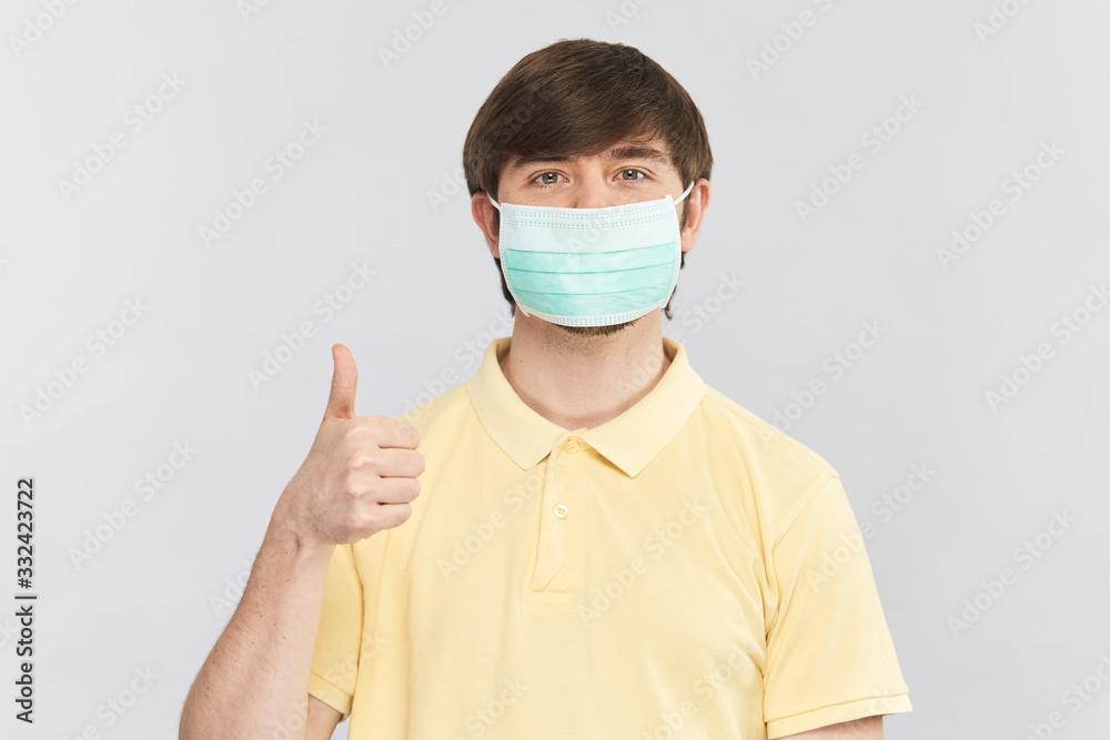 man in yellow shirt and protective sterile mask showing thumbs up gesture man in yellow shirt and protective sterile mask showing thumbs up gesture