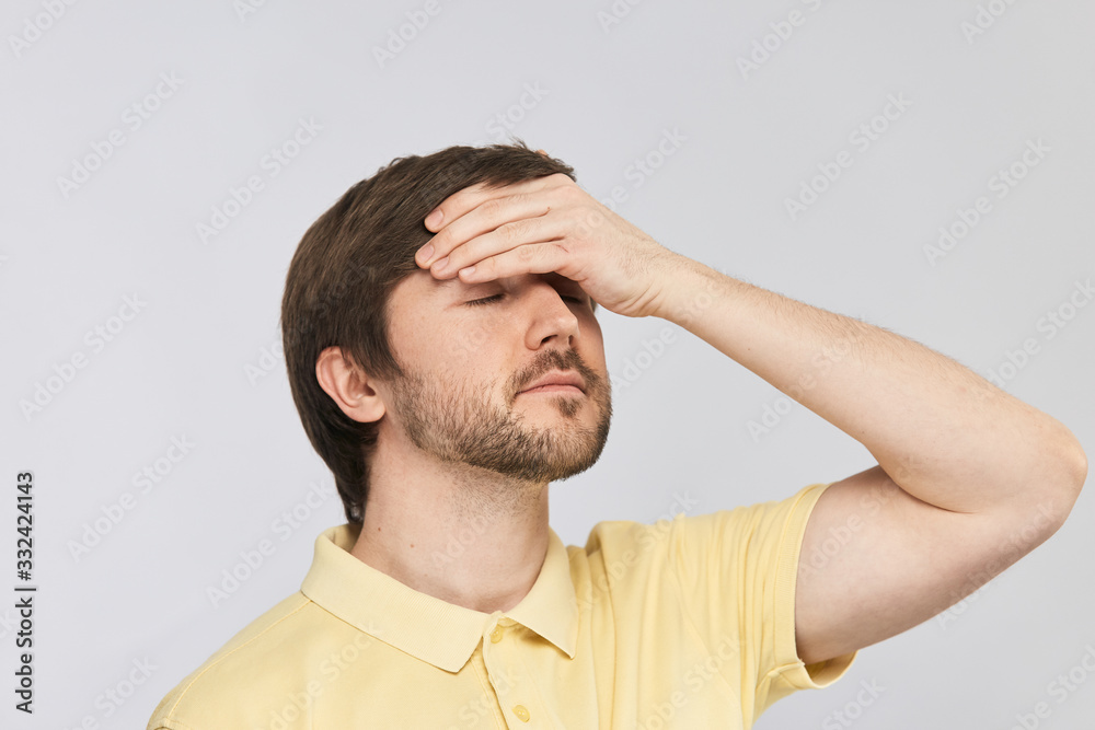young handsome man holding arm on his forehead to measure the temperature young handsome man holding arm on his forehead to measure the temperature