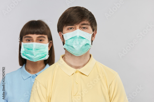 man in yellow shirt ans respiratory mask looking to the camera and girl in protection mask behind
