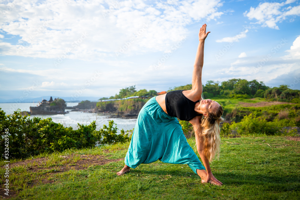 Outdoor yoga practice. Young woman practicing Utthita Trikonasana ...