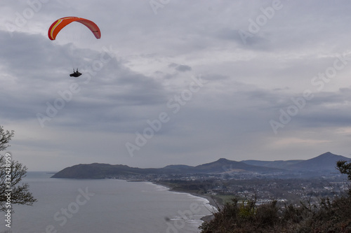 Success concept. A man paragliding in a clear sky on the coast of Ireland