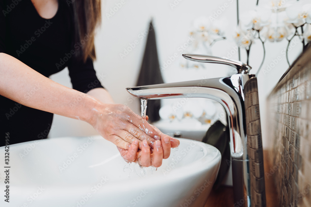Caucasian woman carefully washing hands with soap and sanitiser in home bathroom Caucasian woman carefully washing hands with soap and sanitiser in home bathroom