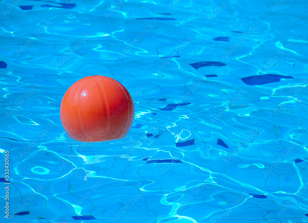 Orange beach ball floating in blue swimming pool, With place for your text.