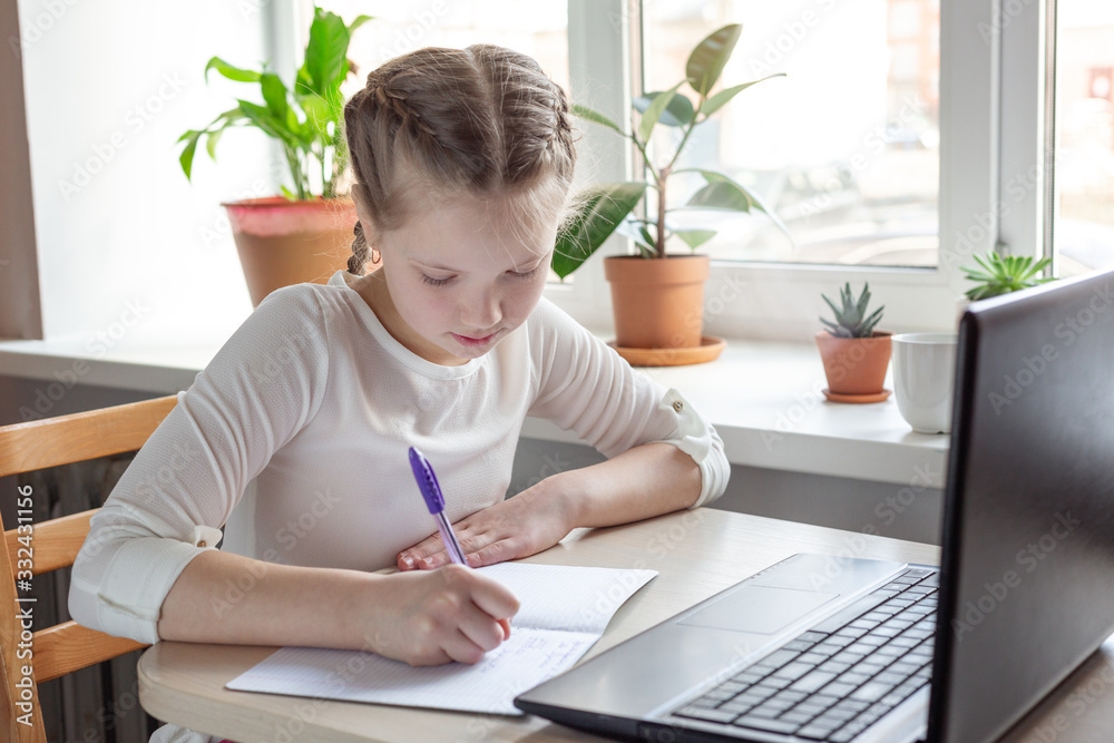 Schoolgirl studying at home using laptop. Home school, online education, home education, quarantine concept Schoolgirl studying at home using laptop. Home school, online education, home education, quarantine concept