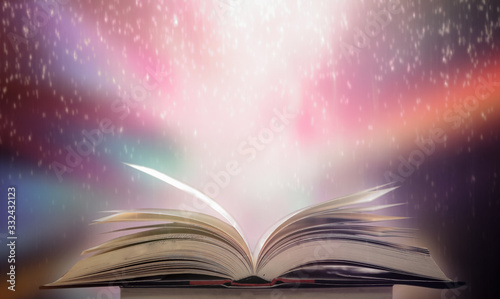 Imagine a picture book of an ancient book opened on a wooden table with a sparkling golden background. With magical power, magic, lightning around a glowing glowing book In the room of darkness © Ping198