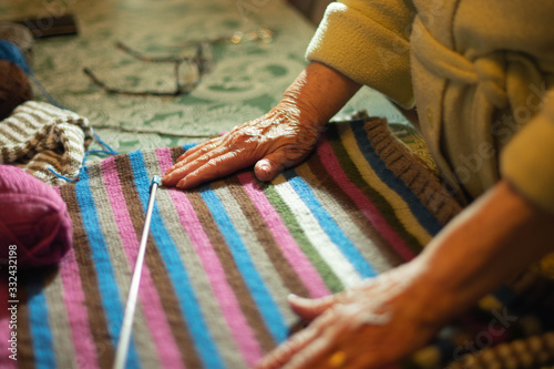 wrinkled hands on the wool garment and a knitting needle