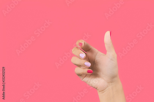 Fotografie Closeup view photography of one manicured beautiful female hand making gesture by empty hand as if holding invisible object in palm isolated on bright pink background