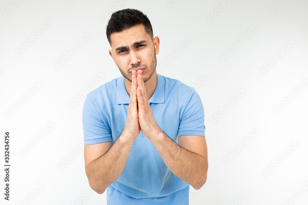 man in a blue T-shirt prays on a white studio background man in a blue T-shirt prays on a white studio background