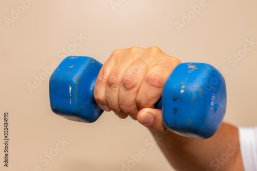 Man exercising his arm with a small blue dumbbell. Muscle exercise