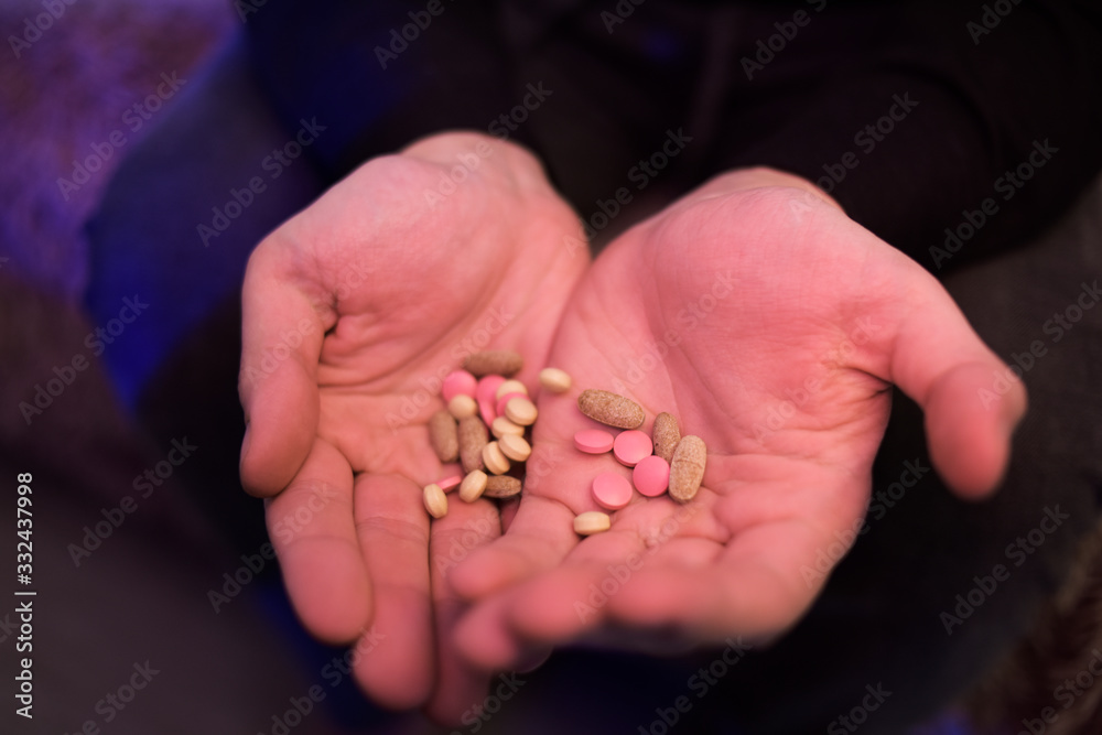 A man holds pills in his hands. Male hands hold many pills. Hands hold pink, white pills, medicine. Coronavirus tablets. A man holds pills in his hands. Male hands hold many pills. Hands hold pink, white pills, medicine. Coronavirus tablets.