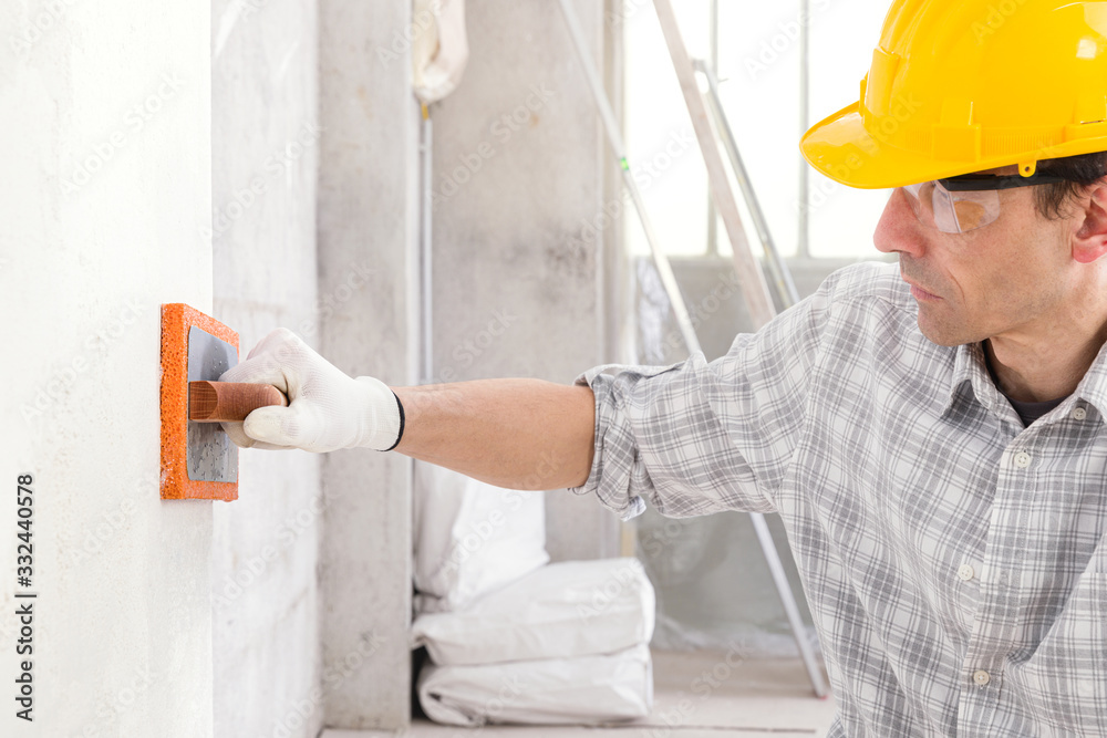 Builder smoothing new plaster on an interior wall Builder smoothing new plaster on an interior wall