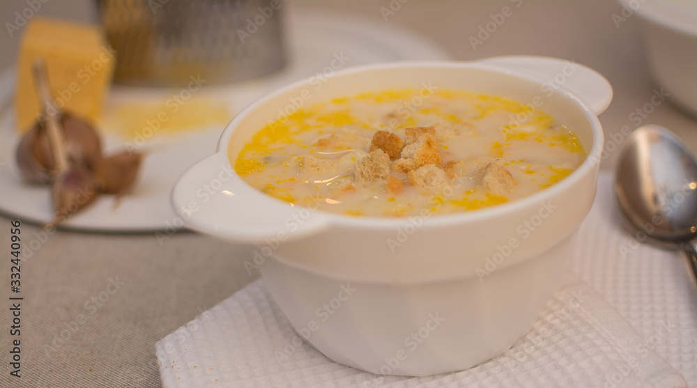 Puree soup with cheese in a white ceramic bowl on a white napkin. Puree soup with cheese in a white ceramic bowl on a white napkin.