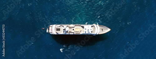 Aerial drone ultra wide top down photo luxury mega yacht with wooden deck anchored in Aegean deep blue sea