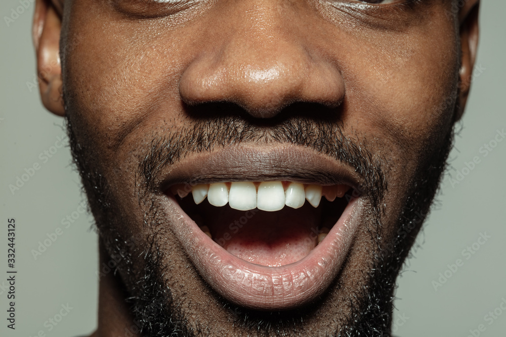 Laughting. Close up of face of beautiful african-american young man, focus on mouth. Human emotions, facial expression, cosmetology, body and skin care concept. Well kept skin. Wellbeing. Laughting. Close up of face of beautiful african-american young man, focus on mouth. Human emotions, facial expression, cosmetology, body and skin care concept. Well kept skin. Wellbeing.