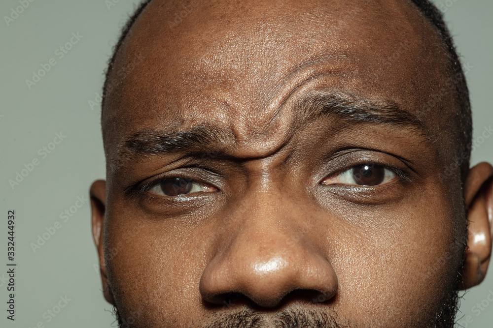 Obraz premium Asking. Close up of face of beautiful african-american young man, focus on eyes. Human emotions, facial expression, cosmetology, body and skin care concept. Well kept skin. Wellbeing.