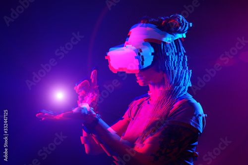 Woman is using virtual reality headset. Neon light studio portrait. Image with glitch effect.