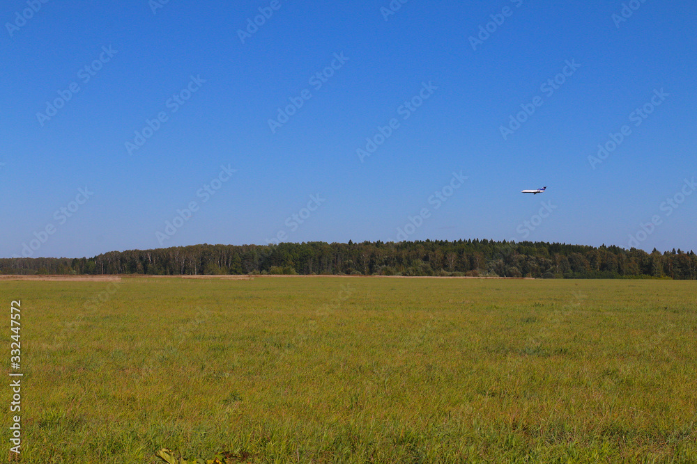 plane on a blue sky on the background of woods and fields plane on a blue sky on the background of woods and fields