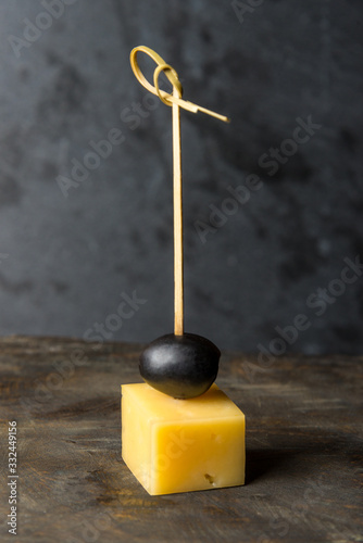 tasty canapes with cheese on a small skewer on a gray background. Vertical frame