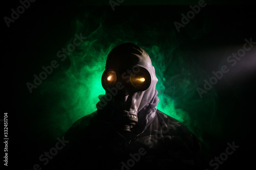 Fototapeta Naklejka Na Ścianę i Meble -  Gas mask with clouds of smoke on a dark background. Sign of radioactive contamination. Means for radiation protection. Danger of carbon monoxide poisoning.