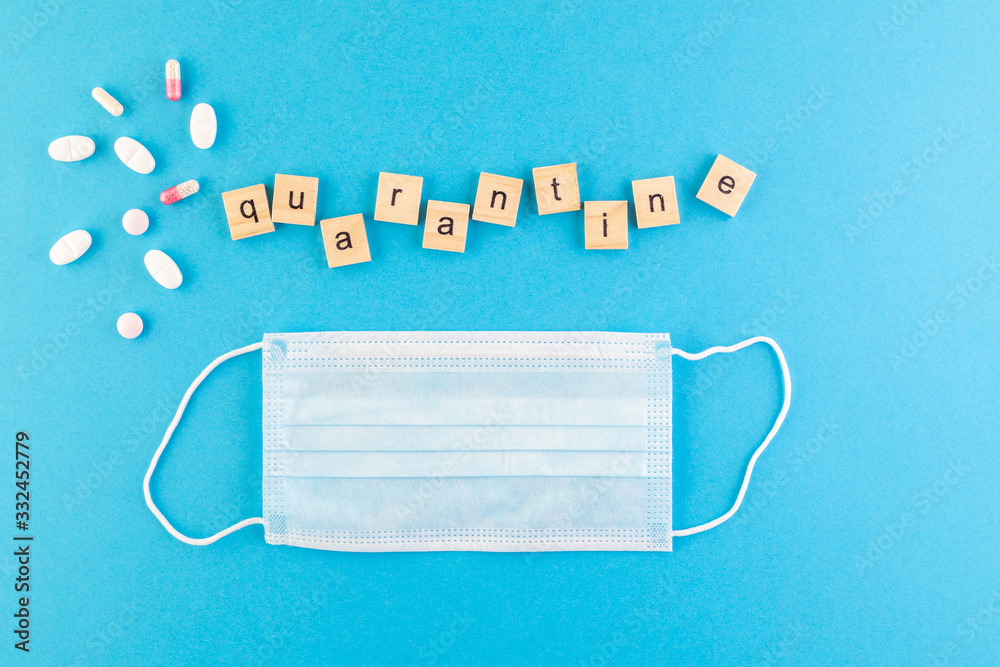 The inscription Quarantine laid out of wooden cubes on a blue background. The inscription Quarantine laid out of wooden cubes on a blue background.