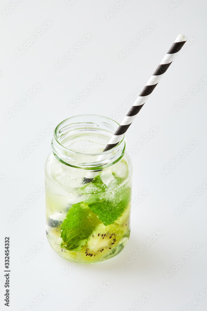 Kiwi Mojito cocktail with mint, kiwi, ice cubes and paper straw on white bricks background Kiwi Mojito cocktail with mint, kiwi, ice cubes and paper straw on white bricks background