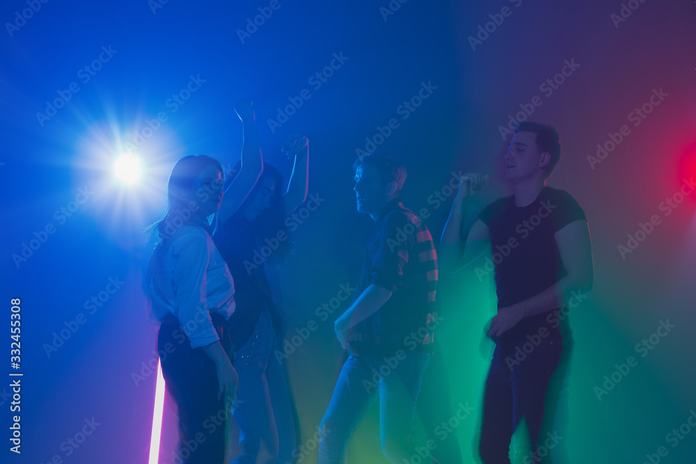 Cheering dance party, performance concept. Crowd shadow of people dancing with neon colorful lights raised hands up on dark background. Celebration, holiday, weekend, nightlife and positive vibes.