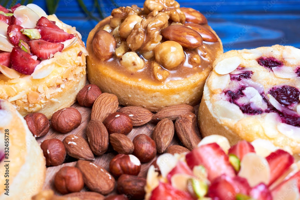 Mini tarts cupcakes with strawberries, walnuts, almond, nuts and blueberries on blue wooden background. Close up Mini tarts cupcakes with strawberries, walnuts, almond, nuts and blueberries on blue wooden background. Close up