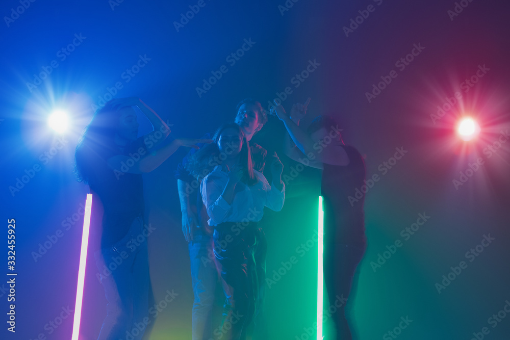 Fototapeta premium Cheering dance party, performance concept. Crowd shadow of people dancing with neon colorful lights raised hands up on dark background. Celebration, holiday, weekend, nightlife and positive vibes.