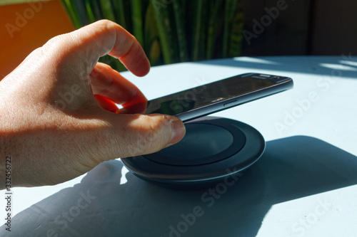 Smartfon odkładany na ładowarkę bezprzewodową.