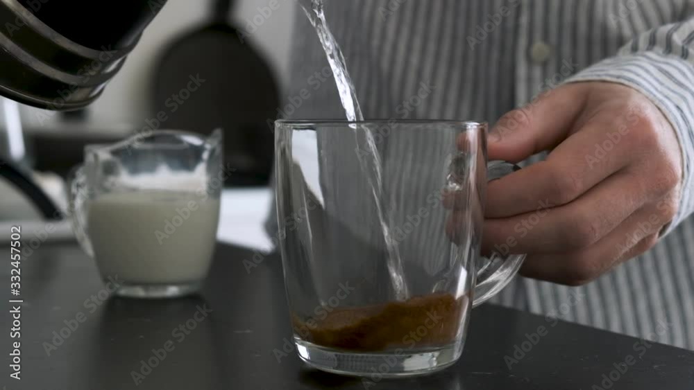 Making instant coffee slow motion of hot water pouring in glass cup. Male person making morning coffee cup Making instant coffee slow motion of hot water pouring in glass cup. Male person making morning coffee cup