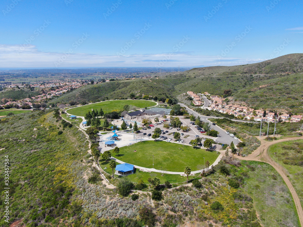 Aerial view of small community park with playground for kids in upper middle class neighborhood with residential subdivision houses during sunny day in San Diego, California, USA.