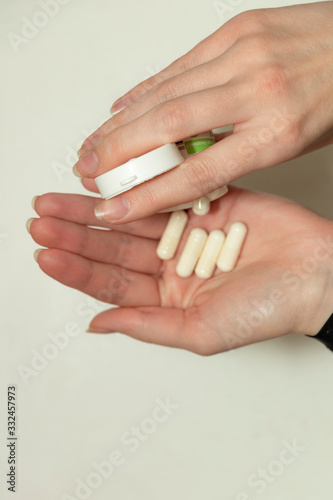 Female hand holds a tablet  capsule in hands. On white background. Pharmaceuticals. Allopathic medicine.