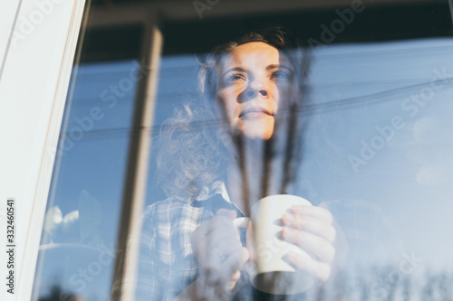 Young blonde woman looking out of the window with a concerned expression on her face