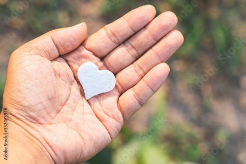 The little white heart rests on the palm of a man's hand.